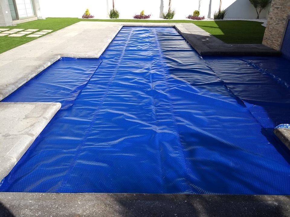Cubierta térmica azul instalada sobre una alberca